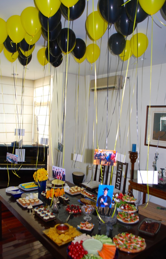 The dining table covered in treats for the graduates and their photos hanging from helium balloons